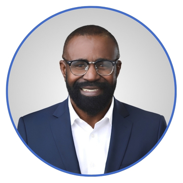 Portrait of a smiling man with a beard and glasses, wearing a navy suit and white shirt, inside a blue circular frame.